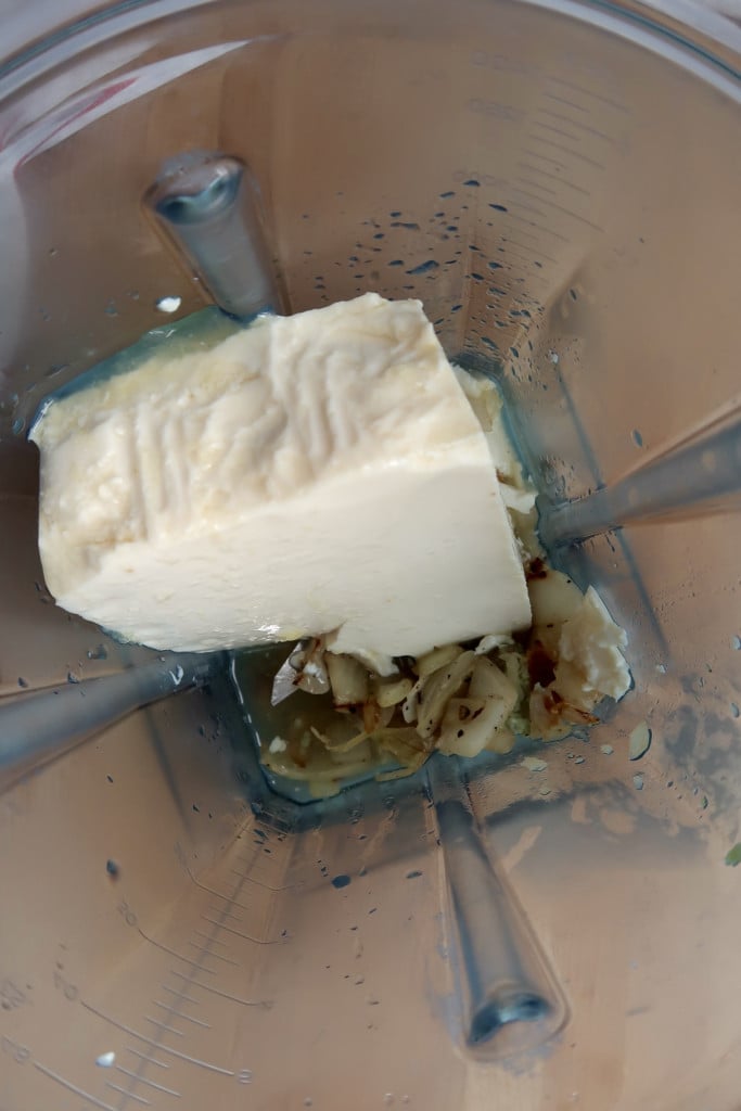 Blender with cooked onion and garlic in it and silken tofu.