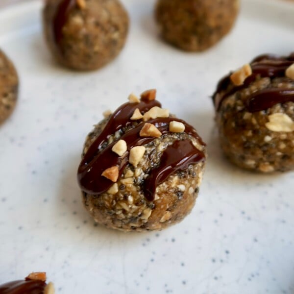 Close up of energy ball with oats, peanut butter and chia seeds with chocolate drizzled on top and peanut pieces.