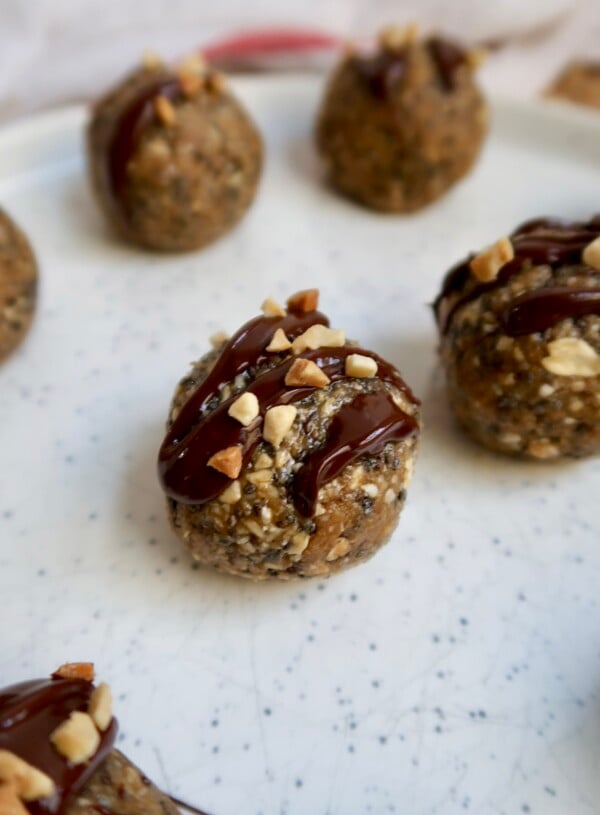 Close up of energy ball with oats, peanut butter and chia seeds with chocolate drizzled on top and peanut pieces.