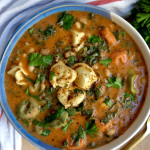 Blue and white bowl with soup with tortellini, kale, basil, and basil off to the side.