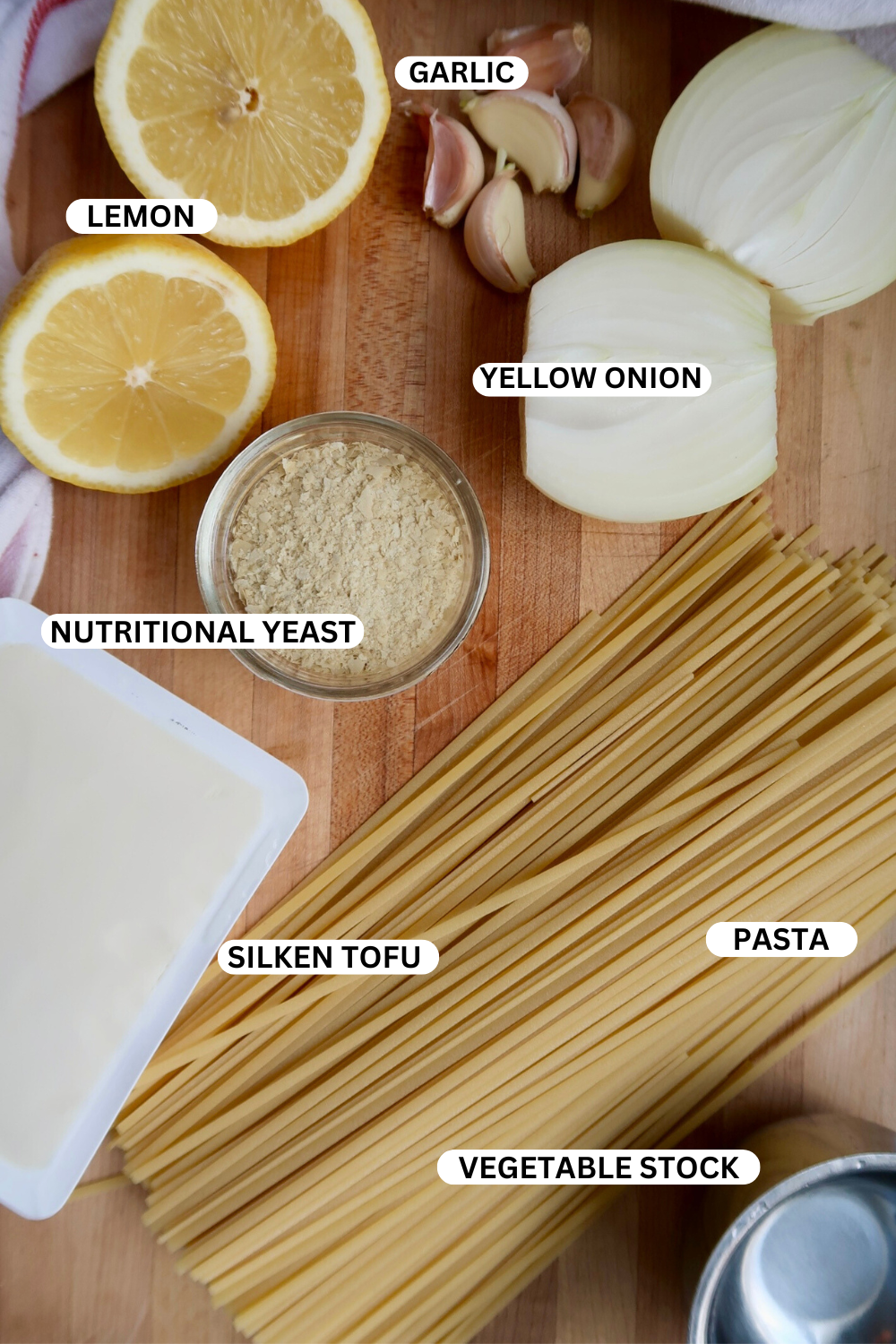 Ingredient flatlay for creamy vegan pasta with silken tofu, lemon, onion and garlic. 