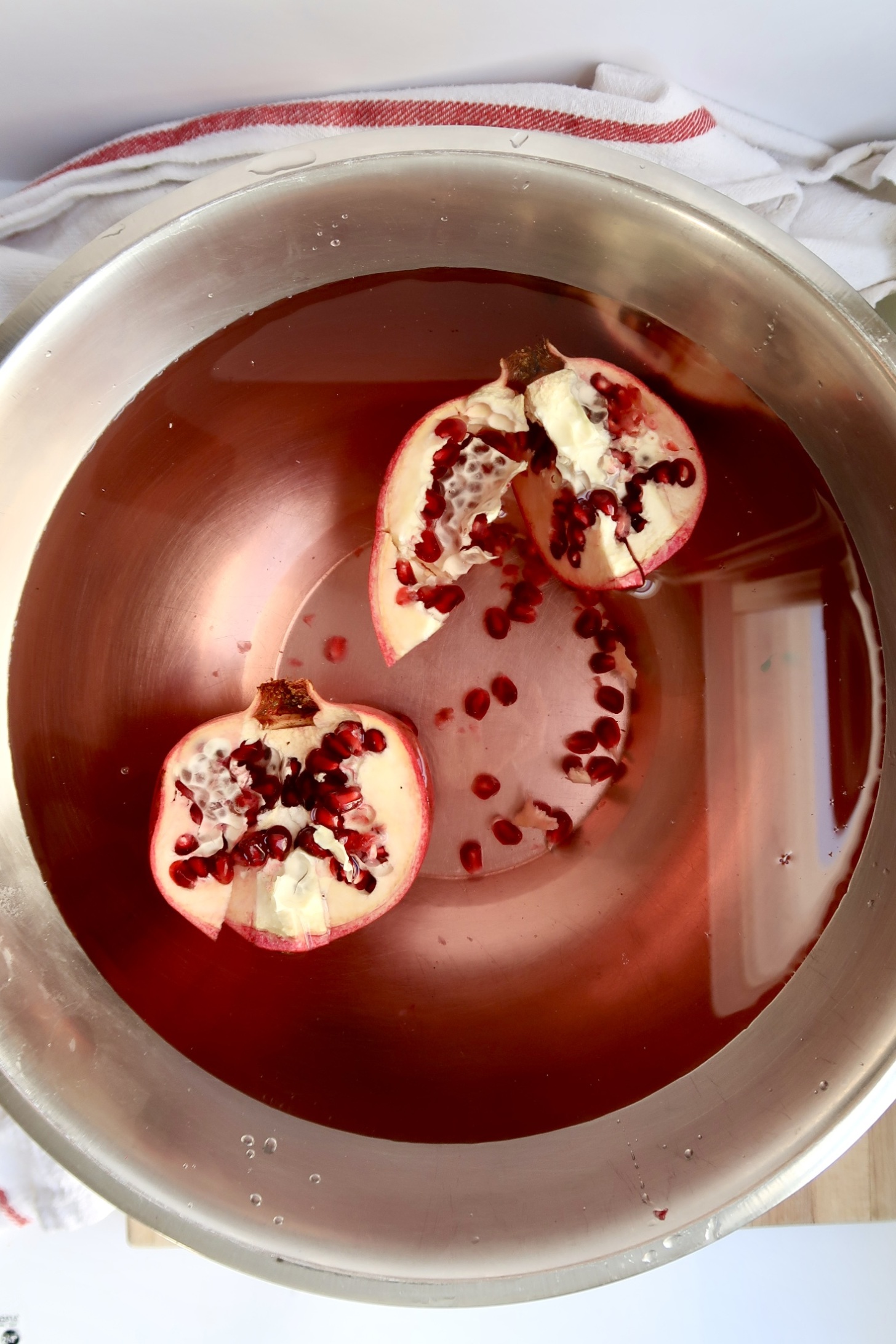 Halved pomegranate in a bowl full of water.