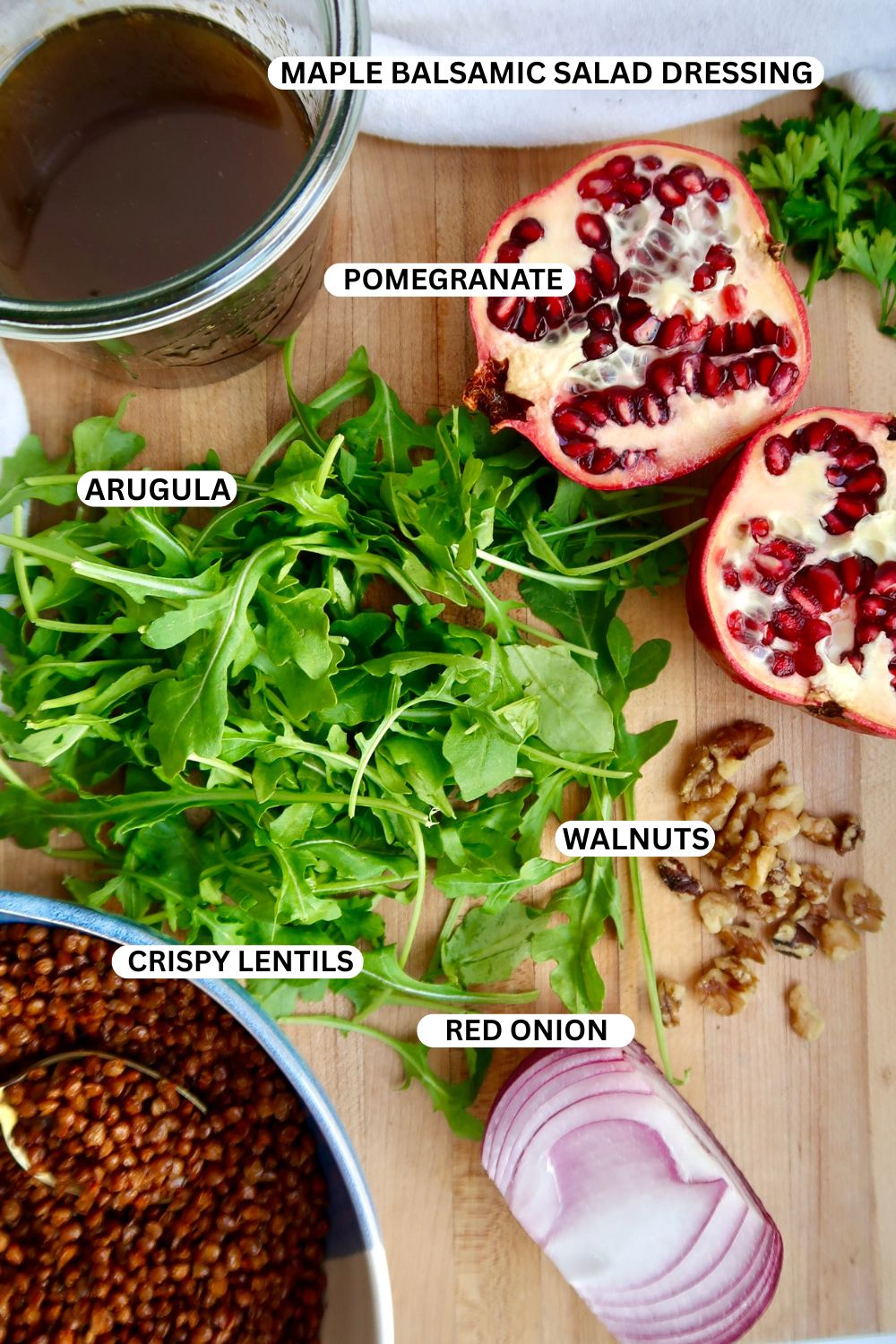 Arugula, pomegranate, balsamic vinaigrette, walnuts, red onion on a cutting board and labeled.