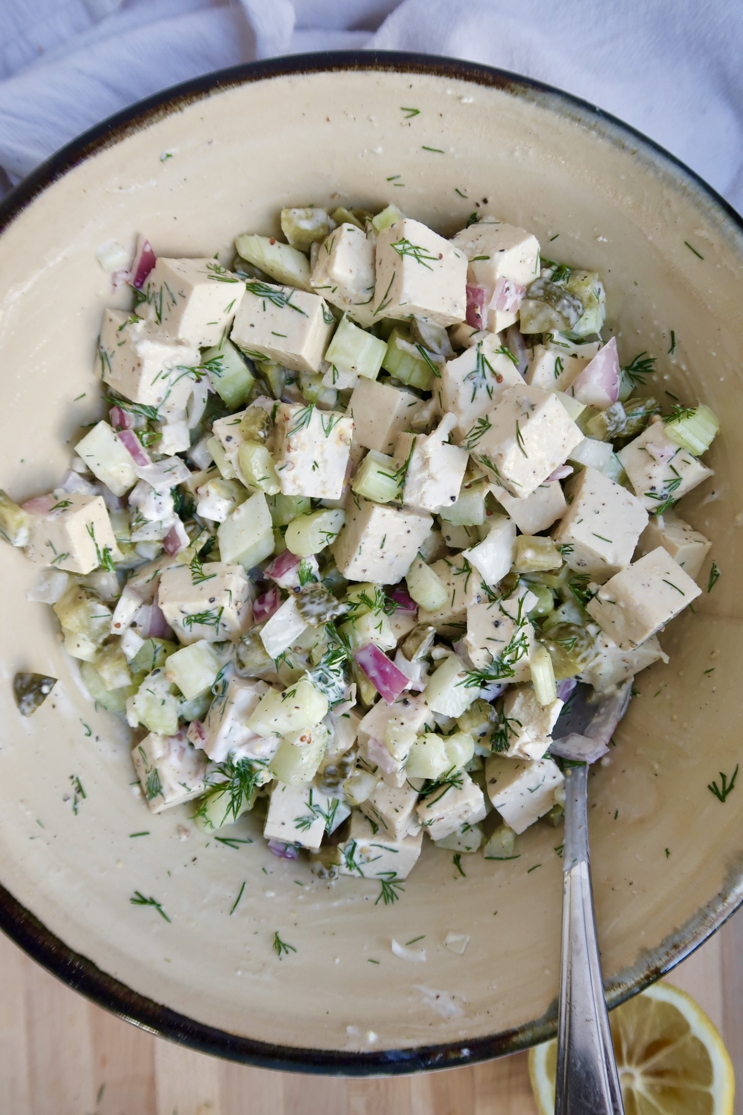 A bowl with tofu chicken salad with a spoon in it.