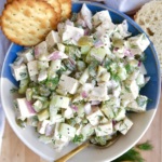 Bowl of tofu chicken salad with crackers to the side and a spoon in the bowl.