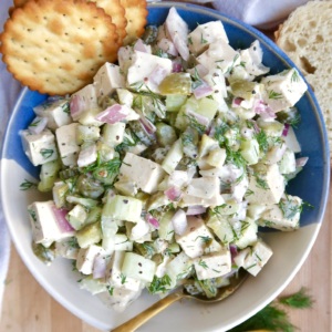 Bowl of tofu chicken salad with crackers to the side and a spoon in the bowl.