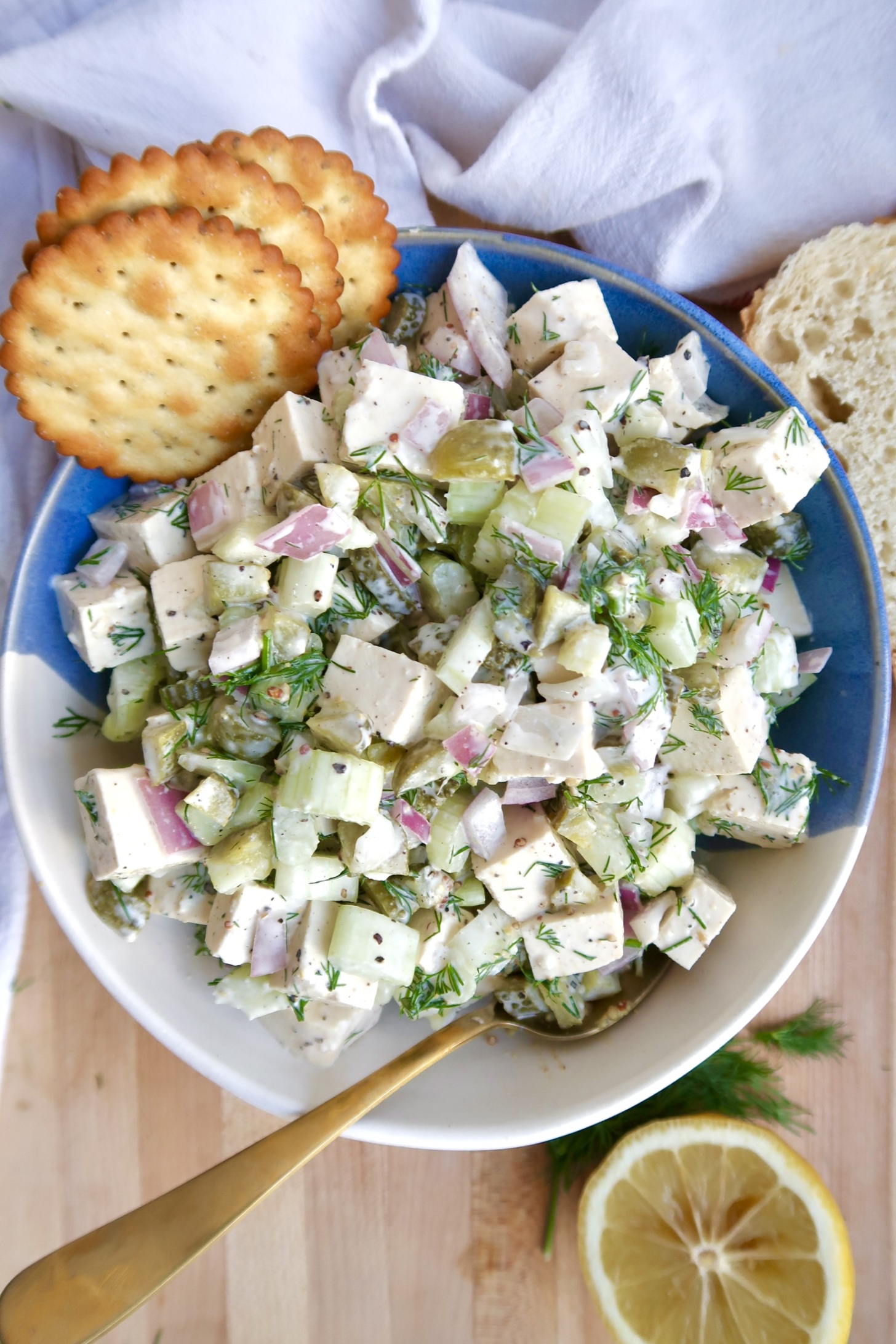 Bowl of tofu chicken salad with crackers to the side and a spoon in the bowl.
