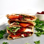 Grilled vegie wrap stacked on a plate with parsley and cranberry sauce to the side.