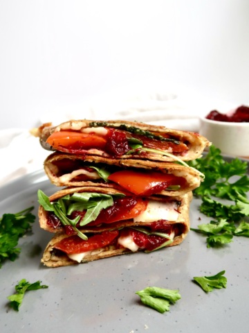 Grilled vegie wrap stacked on a plate with parsley and cranberry sauce to the side.