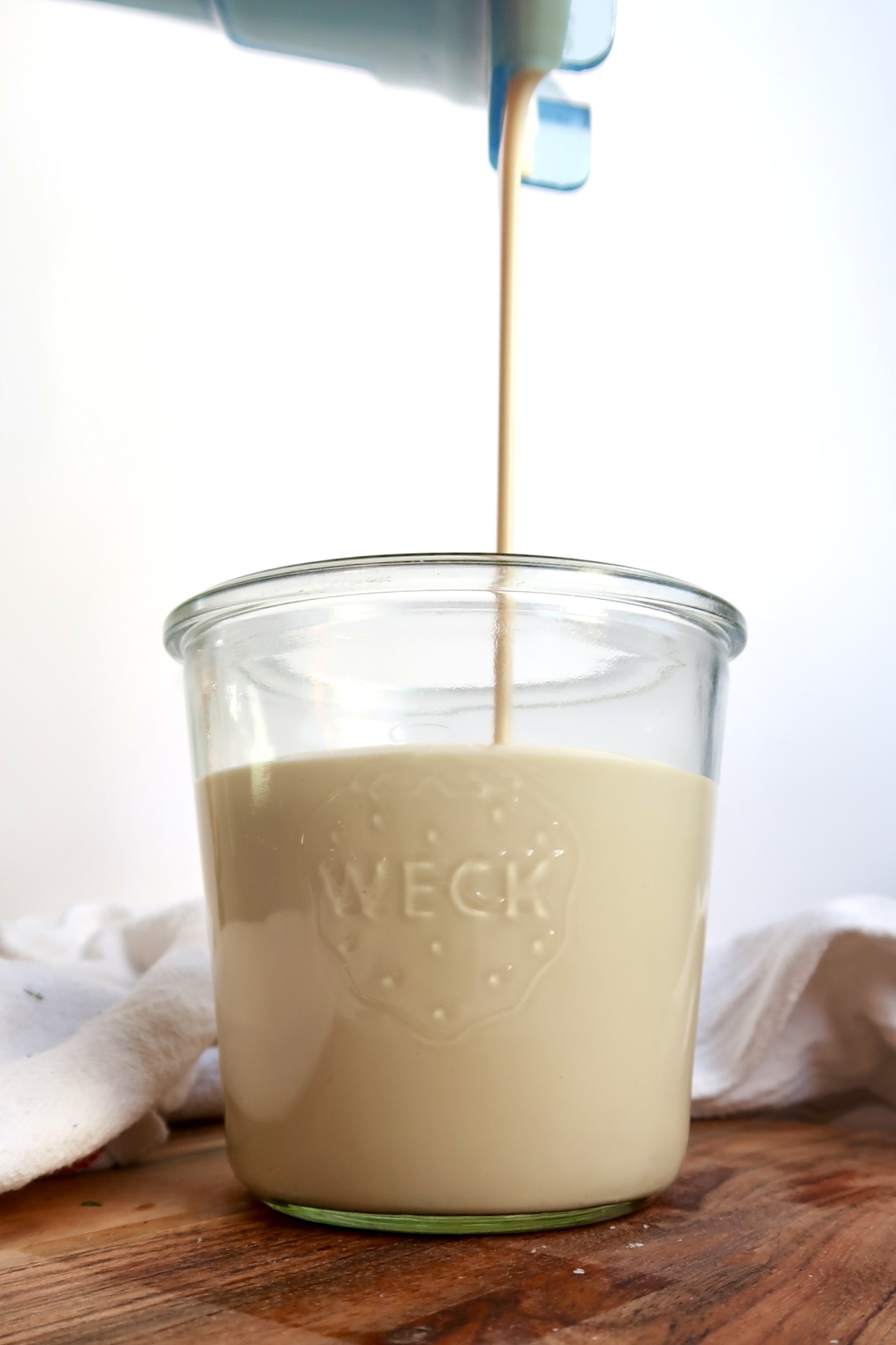 Coconut pudding being poured into a jar before it thickens.