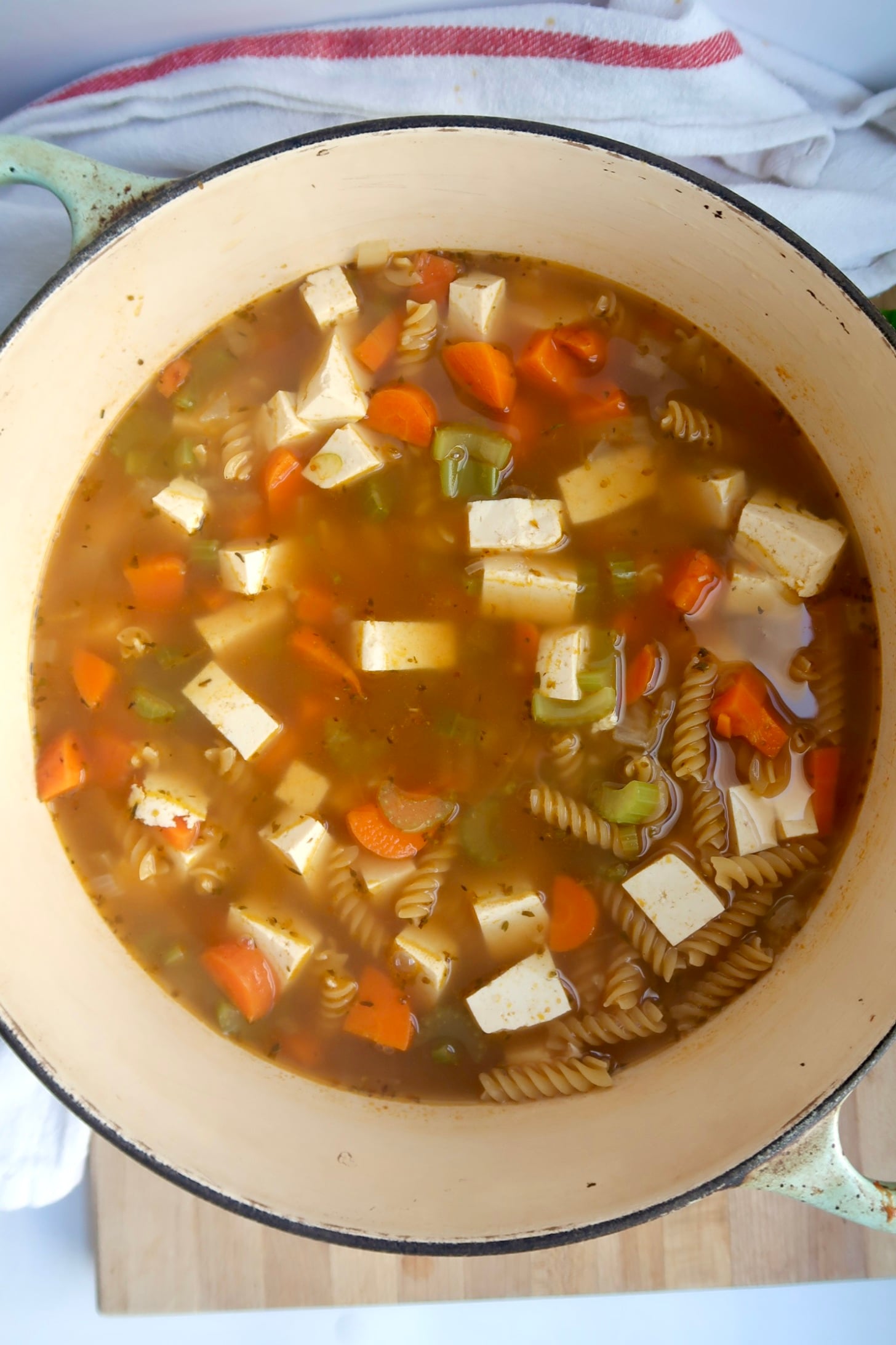 Pot with vegetable stock, diced tofu, carrots and celery.