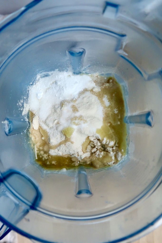 A close-up view of a blender containing flour, oil, and other baking ingredients before mixing.