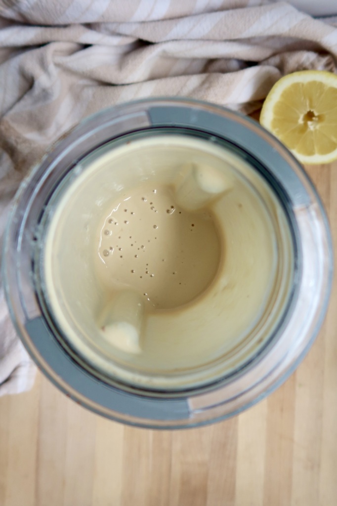 Creamy sauce in a small blender container with a lemon off to the side.