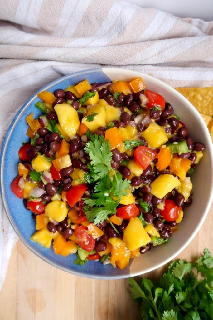 Mango black bean salsa in a bowl with cherry tomatoes, bell pepper and black beans.