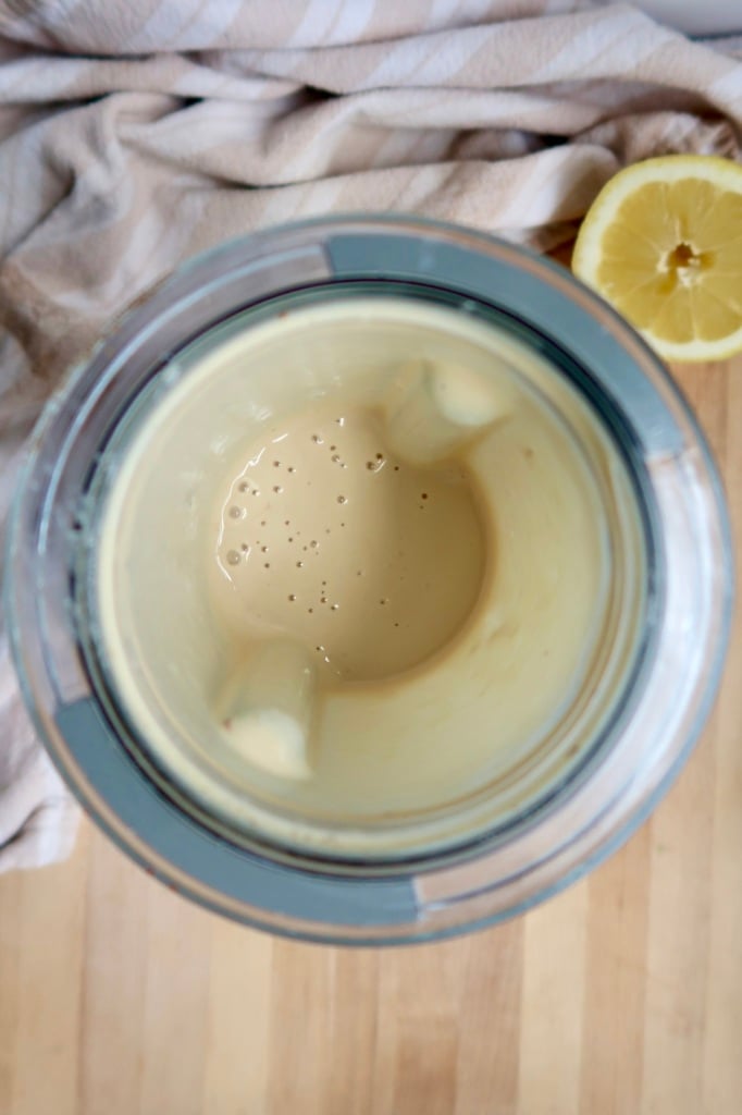 Creamy sauce in a blender with a lemon off to the side.