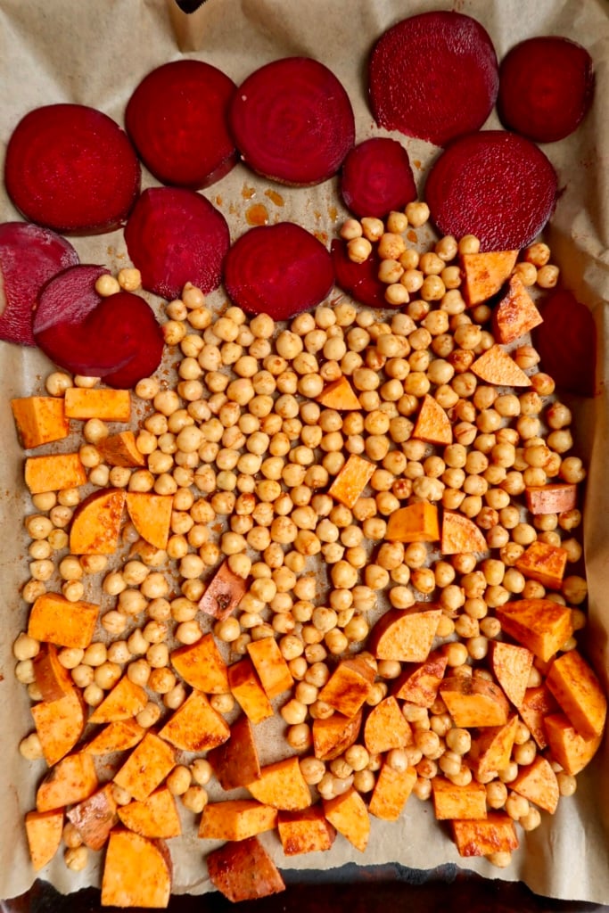 Sheet pan with sliced beets, chickpeas and diced sweet potato uncooked.
