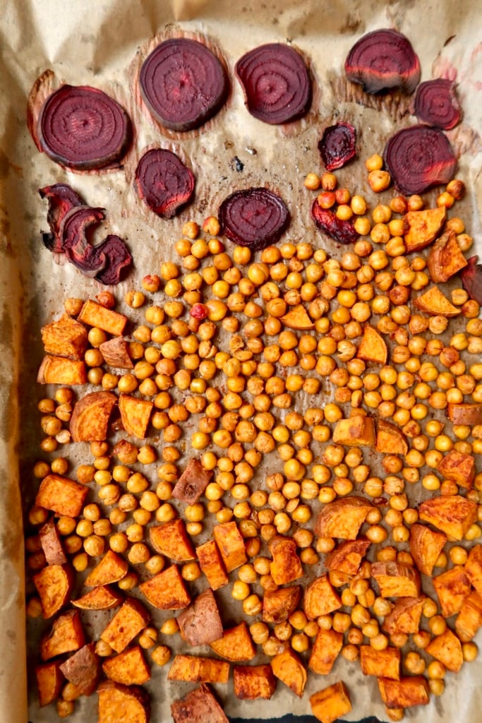 Sheet pan with roasted chickpeas, sweet potato and sliced beets on it.