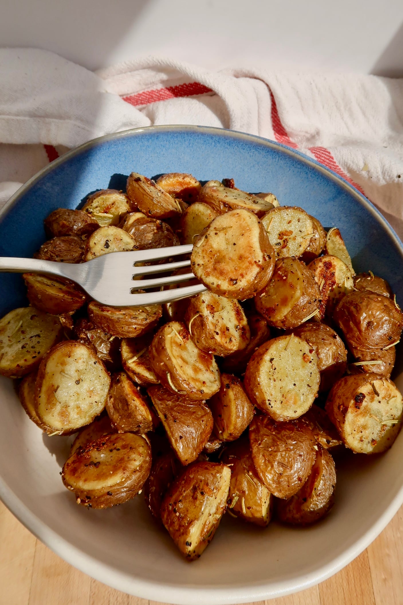 Roasted potatoes in a bowl with a fork piercing them.