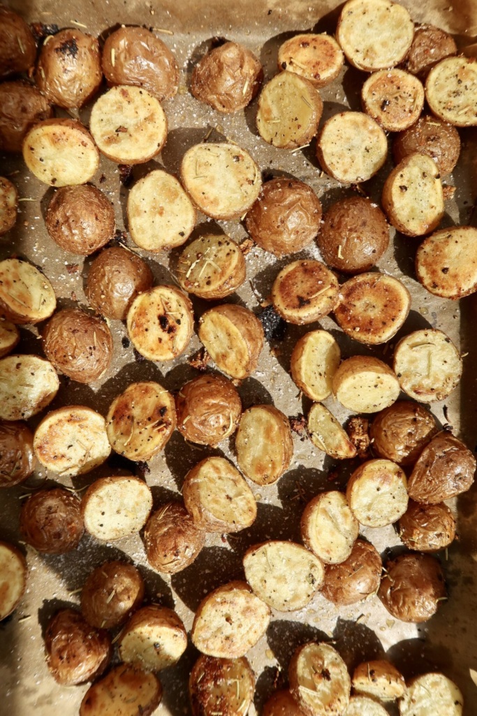 Roasted halved baby potatoes on a sheet pan that are golden brown.