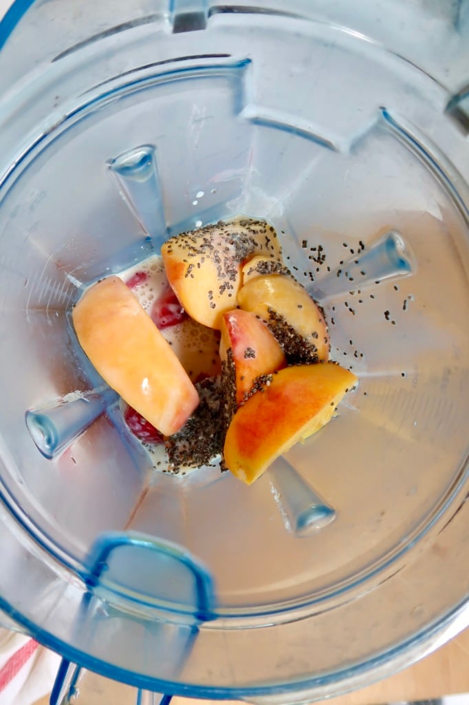 Blender container with sliced peaches, chia seeds and milk.
