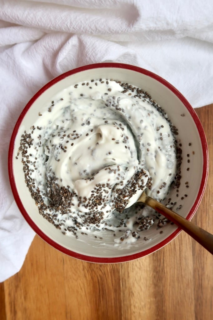 Yogurt in a bowl with chia seeds mixed in in a spoon.